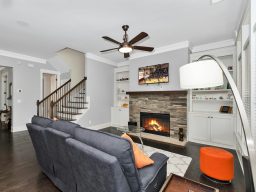 Wohnzimmer mit Kamin, grauem Sofa und Treppe im Hintergrund.