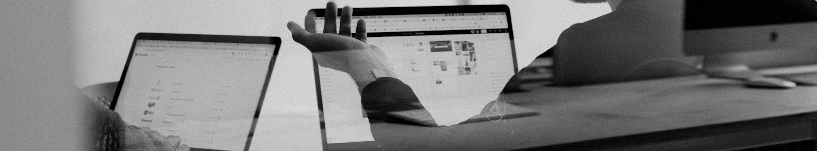 Ein Tisch mit geöffnetem Laptop und mehreren Papierunterlagen.